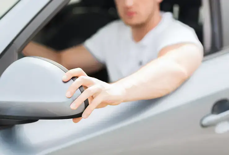 A person adjusting their side mirrors