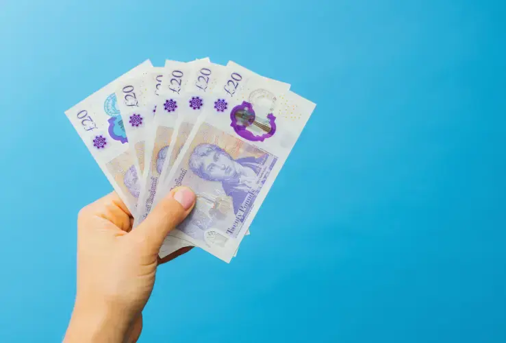 A person holding some £20 notes