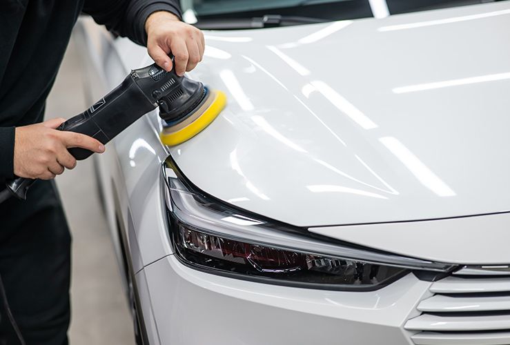 polishing white car hood surface using orbital polishing machine. 