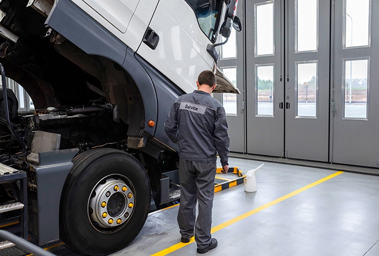 Auto mechanic checking the truck in the garage. Servicing and repairing trucks in a large garage.