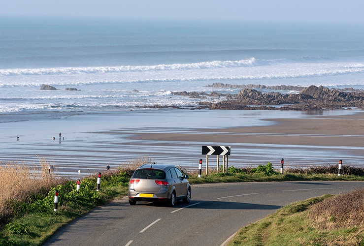 Car driving on UK road with a view of a beach in the background