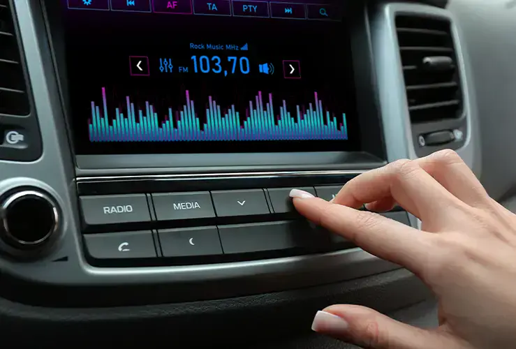 A person putting on the radio in their car